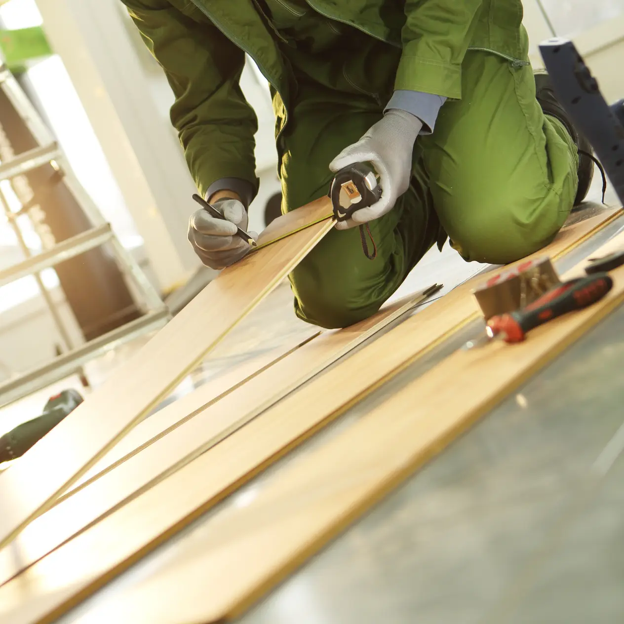 JJ Stone and Flooring crew member measuring and marking flooring planks during installation in Calgary
